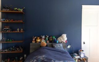 A bed with stuffed animals on it and a blue wall.