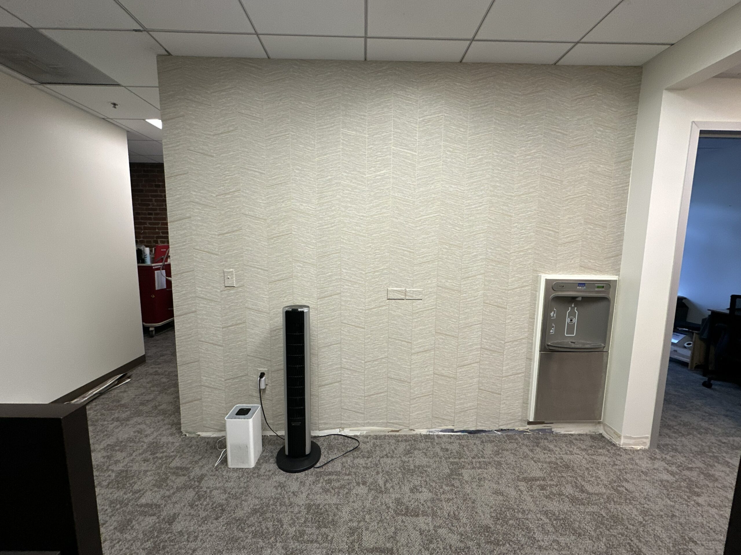Commercial Office Wallpaper Installation and Interior Design Wide shot of a modern commercial office space featuring professionally installed textured chevron wallpaper and a water cooler.