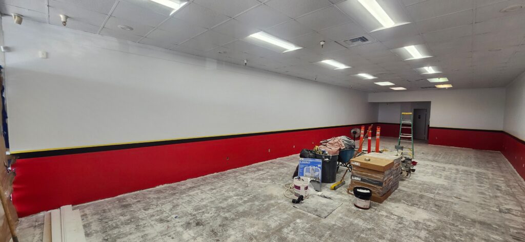White upper wall with red lower wall section and black trim stripe in commercial interior space during painting